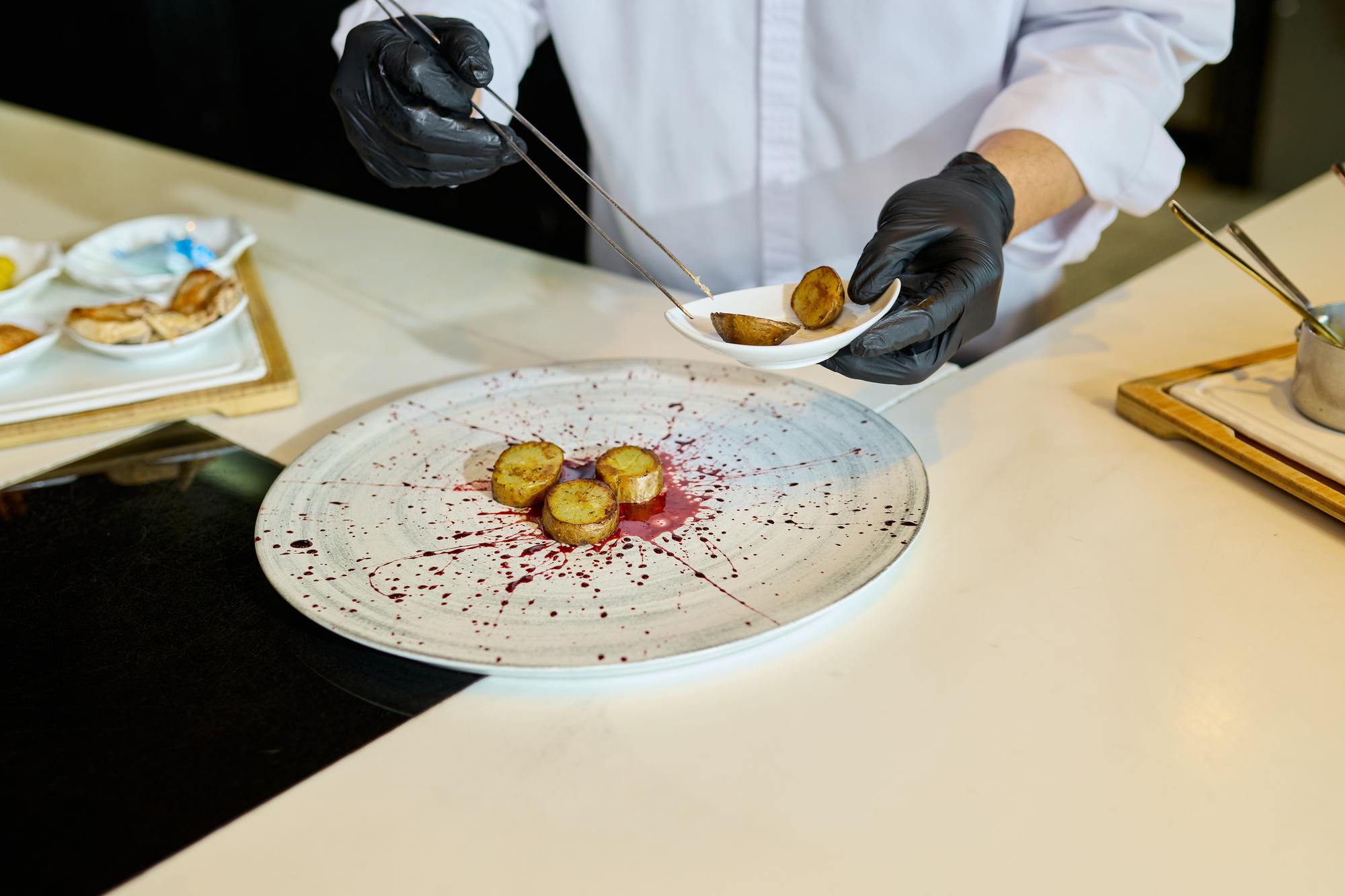 kucharz przygotowujący fine-dining danie z użyciem technik molekularnych